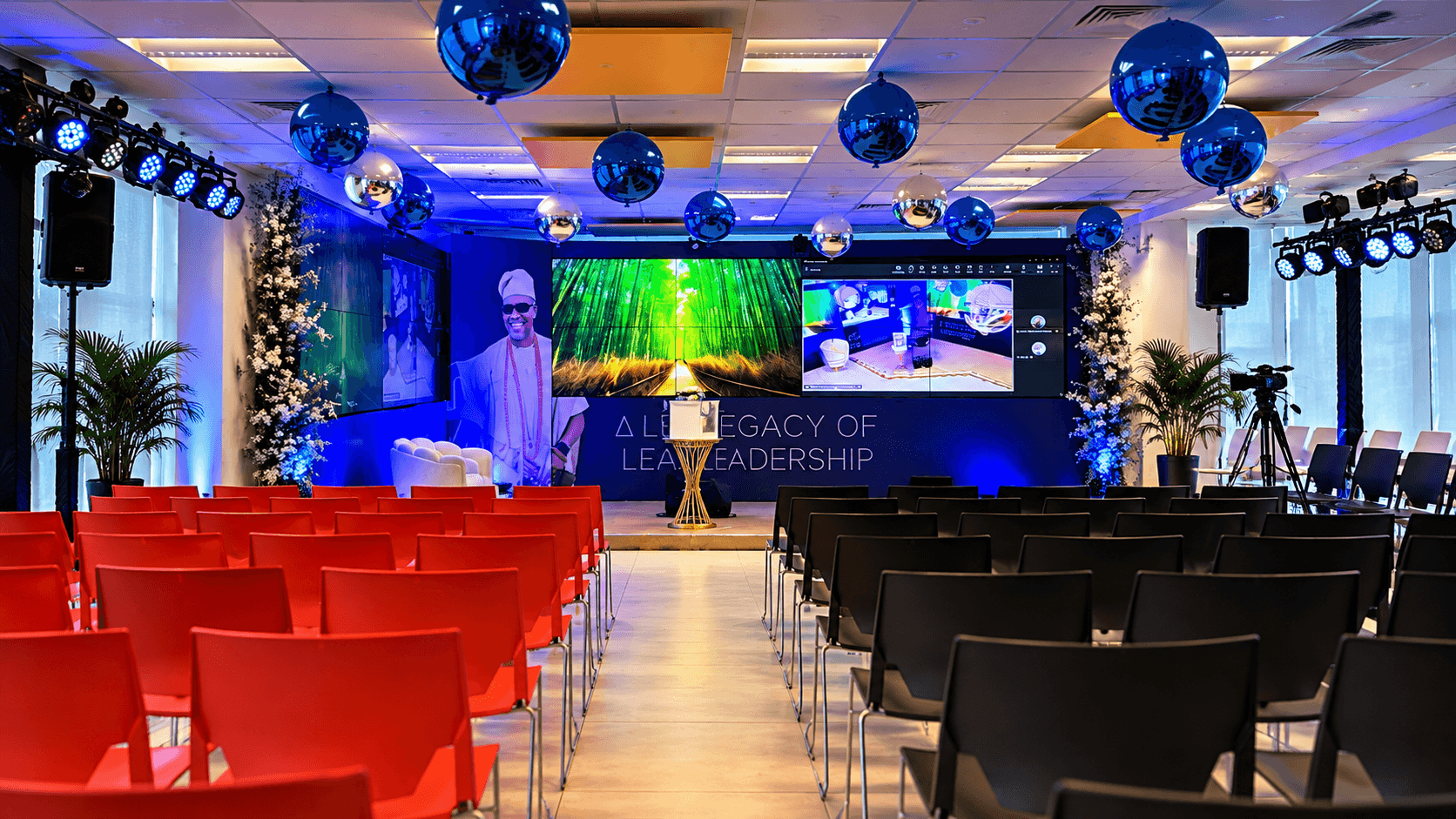 Retirement party — red and black seating facing a blue-lit stage with LED screens and the line "A legacy of leadership"